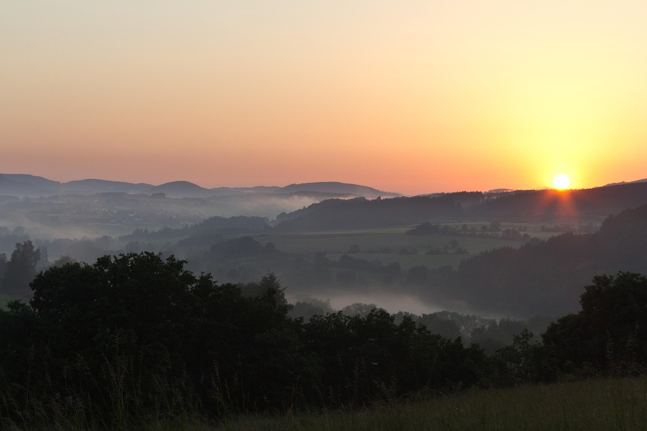 Wanderungen in Hessen sind magisch: Das Bild zeigt einen Sonnenaufgang und Nebel im Tal.